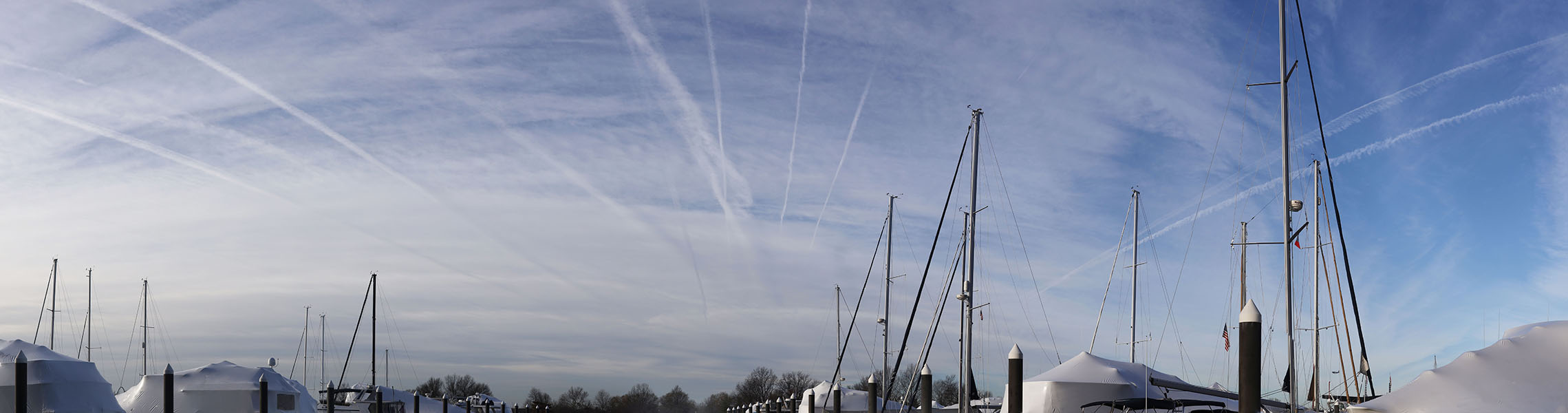 Panoramic Photo of Many Contrails Above a Marina